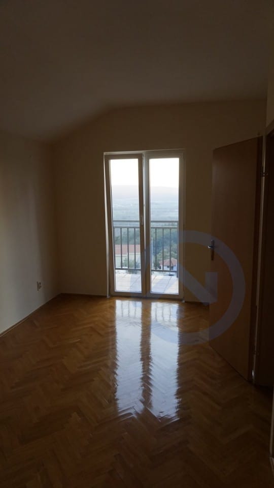Svetla spavaća soba sa parketom i izlazom na balkon s pogledom na planine u kući, Kavač, Crna Gora.