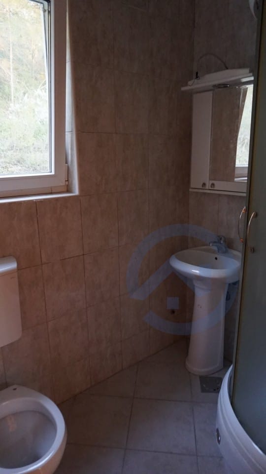 Kupatilo u kući, Kavač, Crna Gora: bež pločice, tuš kabina, umivaonik i prozor s pogledom na prirodu.