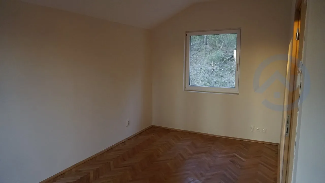 Bright empty bedroom with parquet flooring and a view of nature in a house for sale, Kavac, Montenegro.