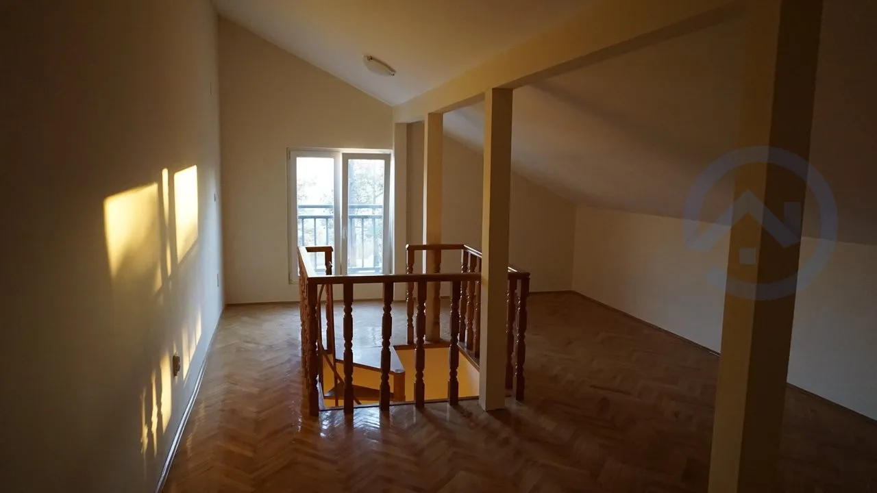 Attic living room with parquet flooring and a wooden staircase in a house, Kavac, Montenegro. Bright room with access to the balcony.