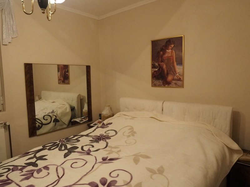 Gemütliches Schlafzimmer mit Doppelbett und Spiegel in einer Villa in Dobrota, Montenegro. Helles Interieur, klassischer Stil.