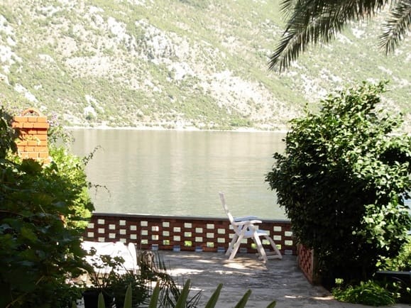 Terasa kuće u Stolivu, Crna Gora, sa pogledom na Bokokotorski zaliv, planine i baštu sa baštenskim nameštajem.