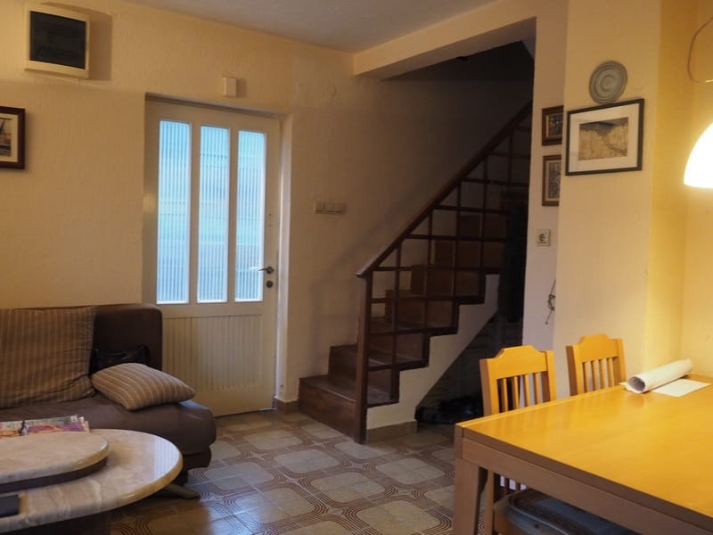 Living room with a wooden staircase and dining area in a house for sale in Đenovići, Montenegro.