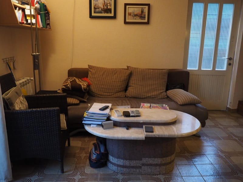 Cozy living room in a house in Đenovići, Montenegro: a brown sofa, a wicker chair, and an original stone coffee table.