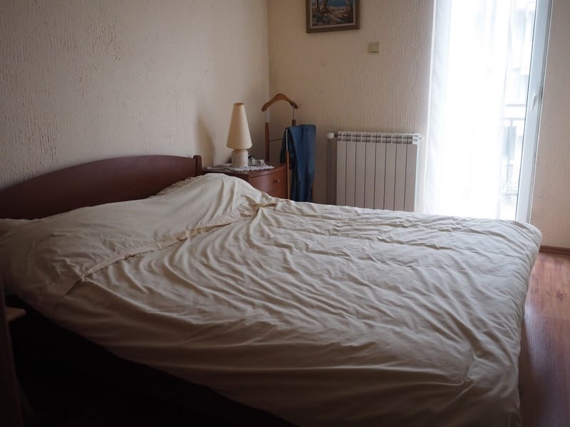 Cozy bedroom with a double bed in a house in Đenovići, Montenegro: light finishes, laminate flooring, and access to the balcony.