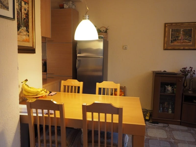 Cozy kitchen in a house in Đenovići, Montenegro: wooden dining table, chairs, refrigerator, and classic interior.
