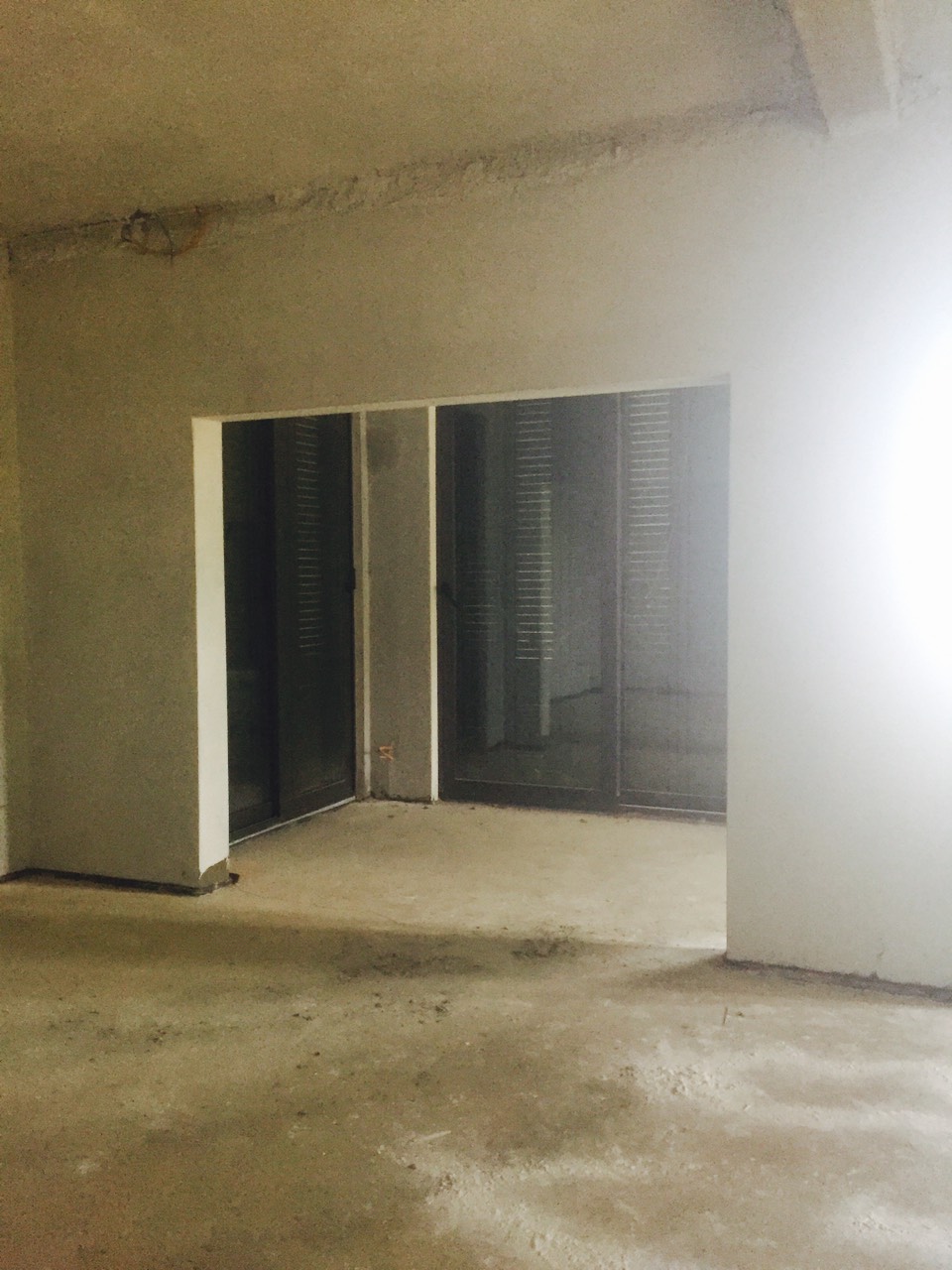 Wohnzimmer im Renovierungsprozess in einer Villa in Herceg Novi, Montenegro: Betonwände und Panoramafenster mit Zugang zur Terrasse.