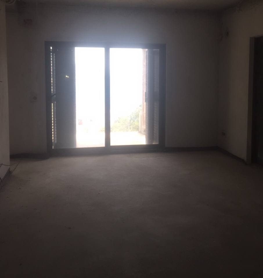Wohnzimmer ohne Ausbau in einer im Bau befindlichen Villa in Herceg Novi, Montenegro, mit Panoramazugang zur Terrasse und Blick auf den Garten.