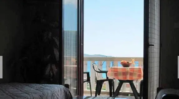 Pogled iz spavaće sobe na terasu sa nameštajem i panoramskim pogledom na more u stanu u Igalu, Crna Gora.