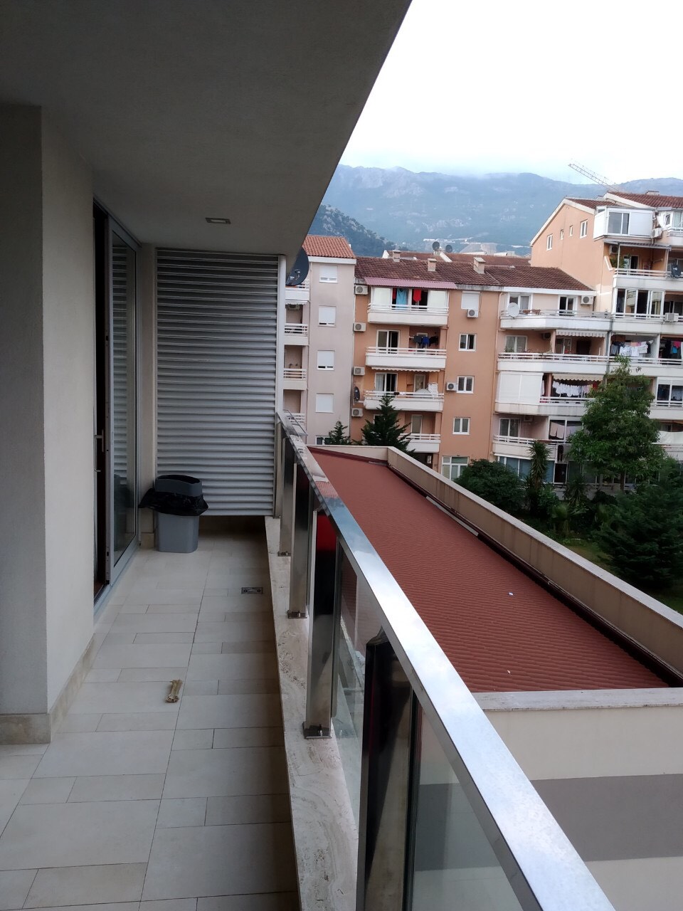 Prostran balkon stana u Budvi, Crna Gora, sa panoramskim pogledom na planine i gradsku izgradnju.