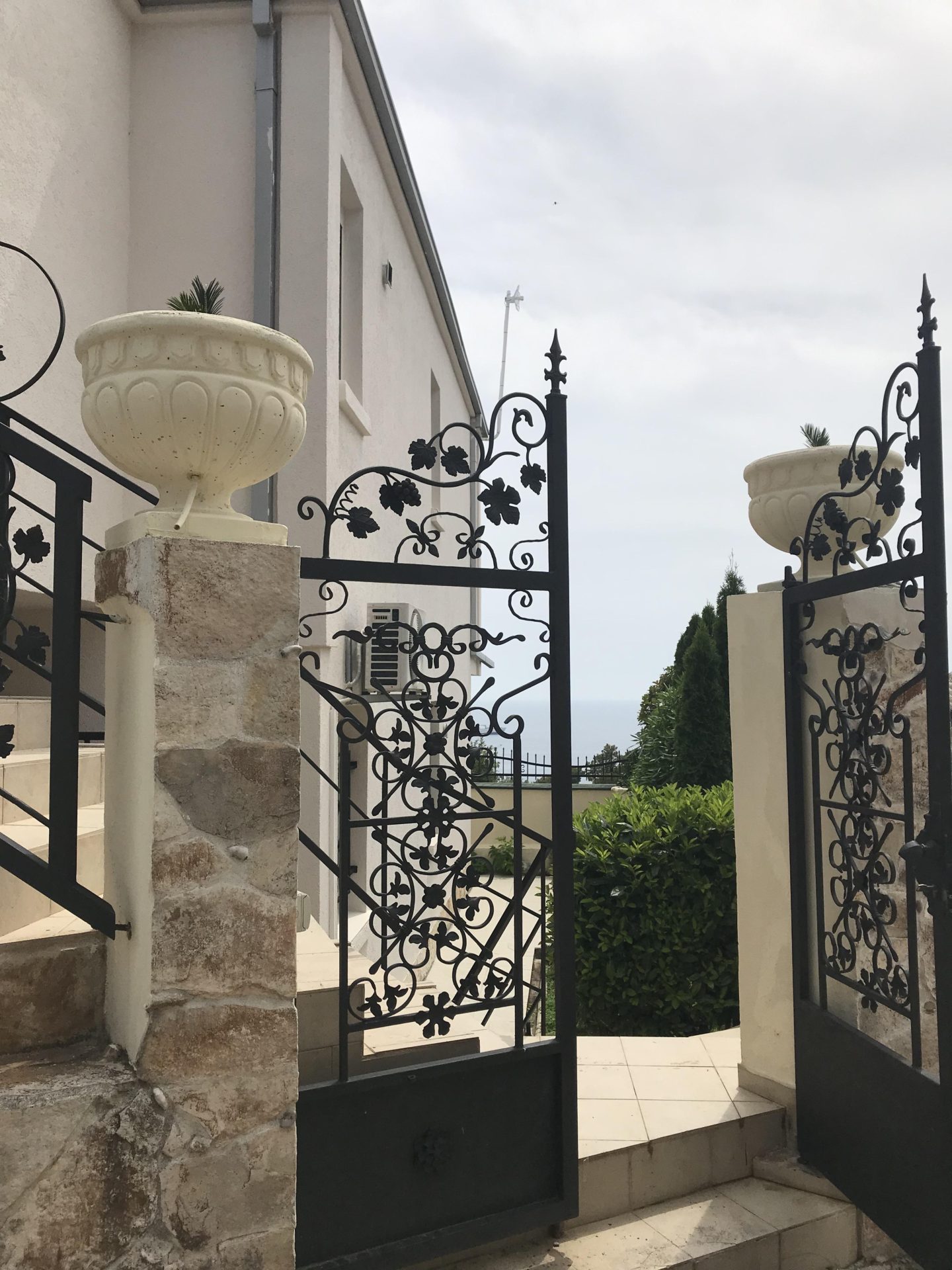 Geschmiedetes Tor und Steintreppe des Hauses in Bar, Montenegro: Blick auf das Grundstück und den Garten.