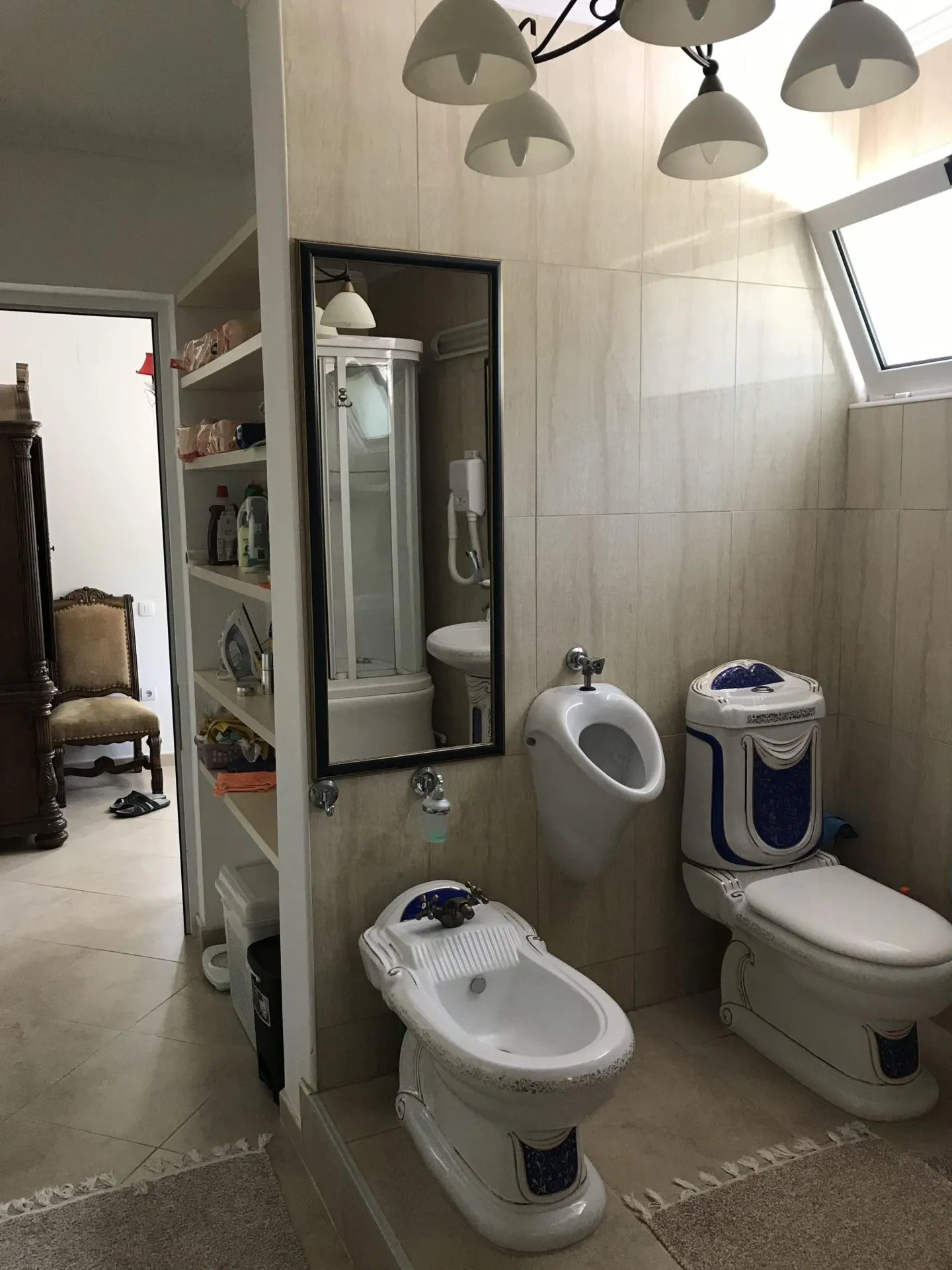 Kupatilo sa bideom, toaletom i pisoarom u kući u gradu Bar, Crna Gora, obloženo svetlim pločicama.