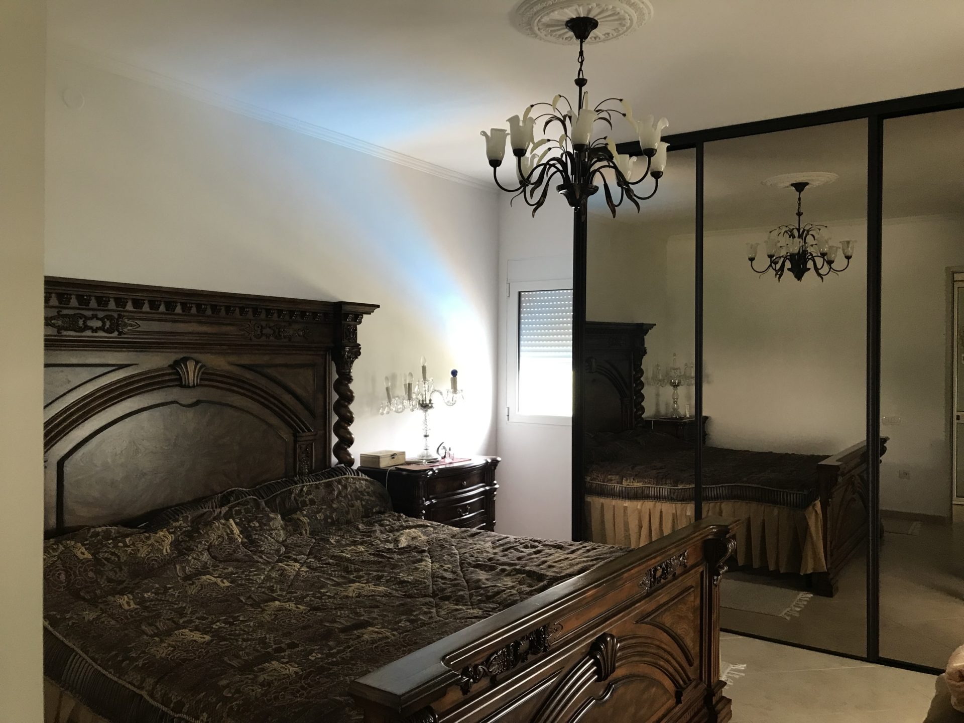 Schlafzimmer im klassischen Stil mit geschnitztem Holzbett und Spiegelschrank in einem Haus, Stadt Bar, Montenegro.