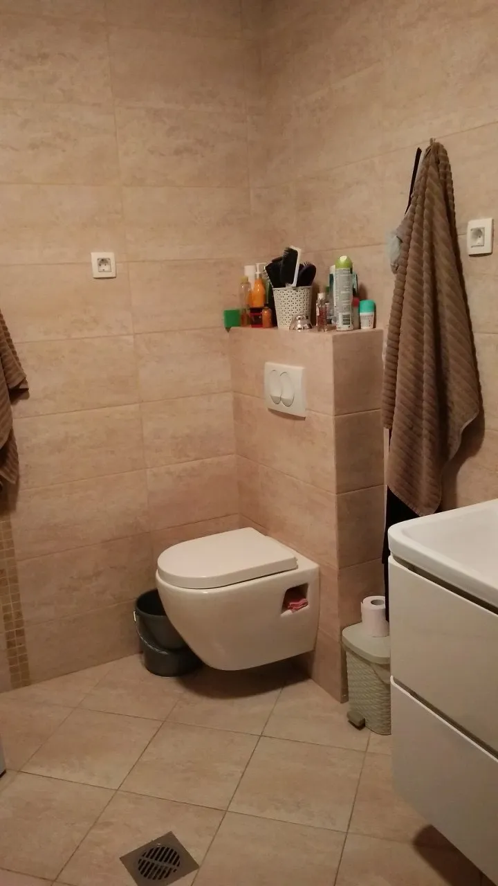 Savremeno kupatilo sa visećom WC šoljom i bež pločicama u stanu u Budvi, Crna Gora.