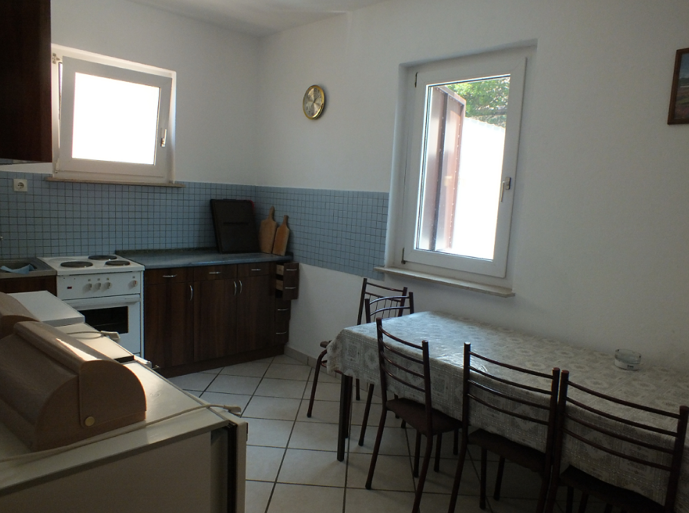 Cuisine lumineuse avec coin repas dans une maison, ville de Bar, Monténégro : meubles de cuisine, cuisinière et table avec chaises.
