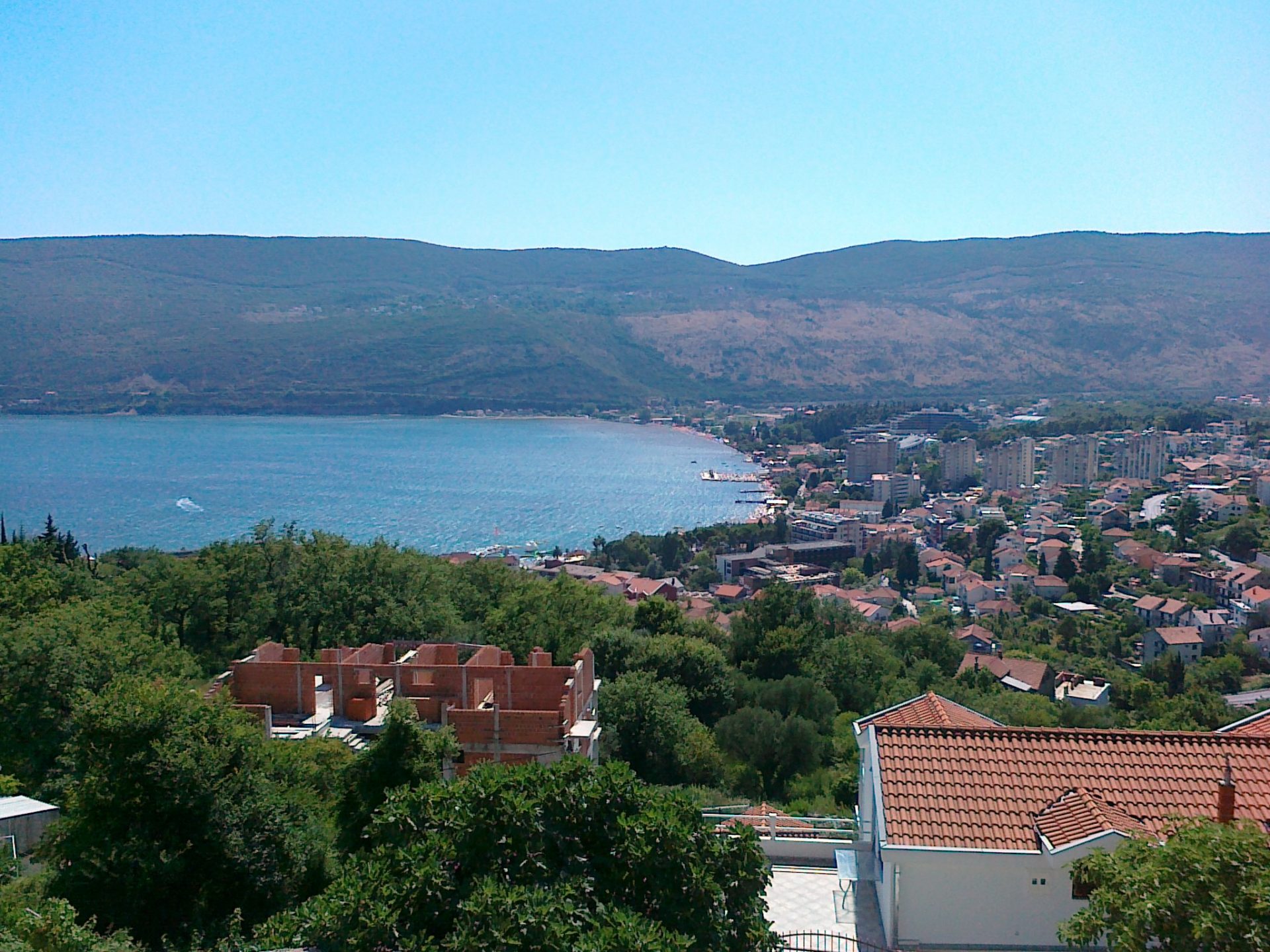 Yeşillikler ve dağlarla çevrili evin terasından Karadağ, Herceg Novi’nin deniz ve şehir panoramik manzarası.