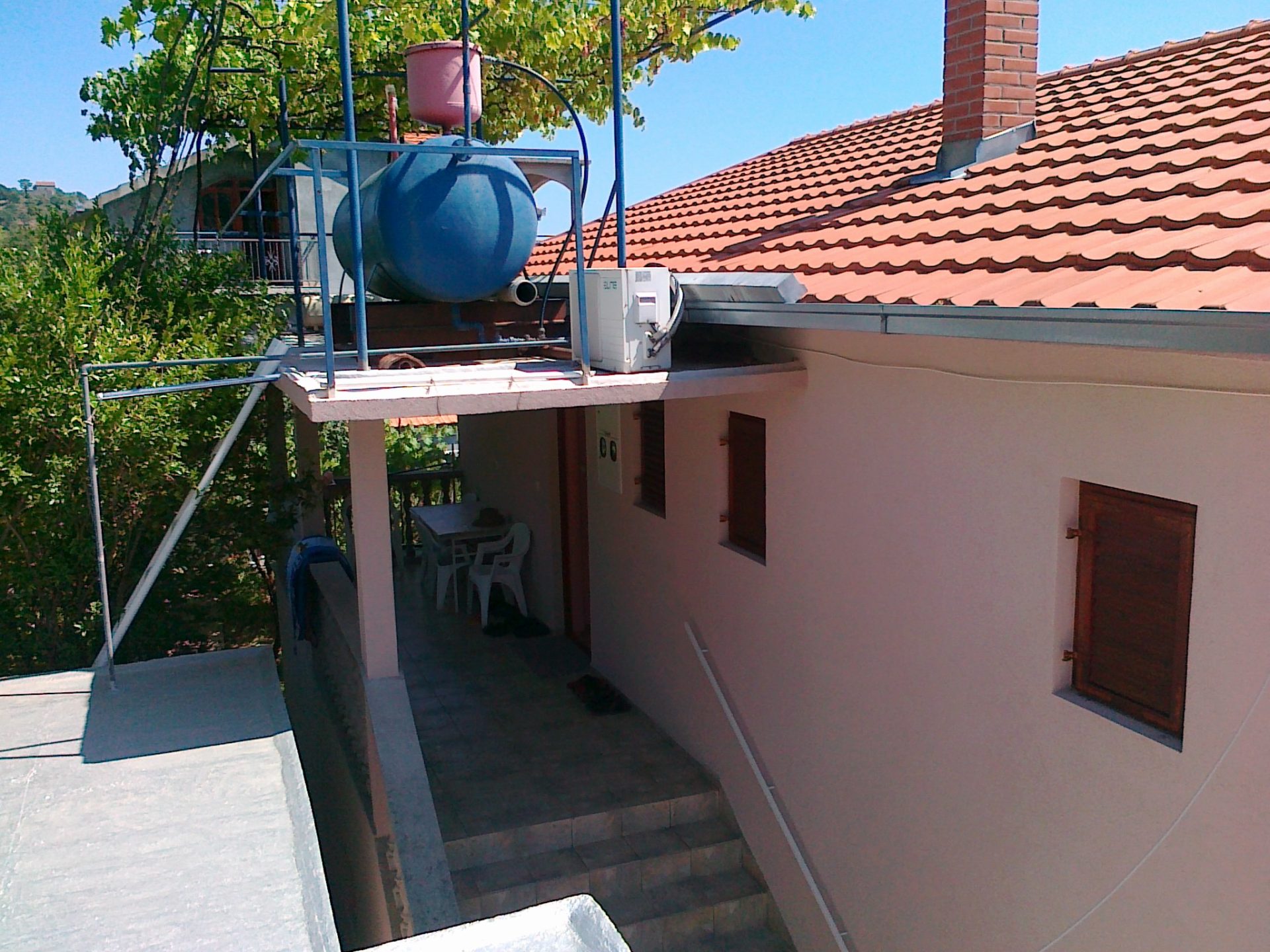 Karadağ, Herceg Novi’de kiremit çatılı ve su deposu olan evin terası: mobilyalı şirin avlu manzarası.