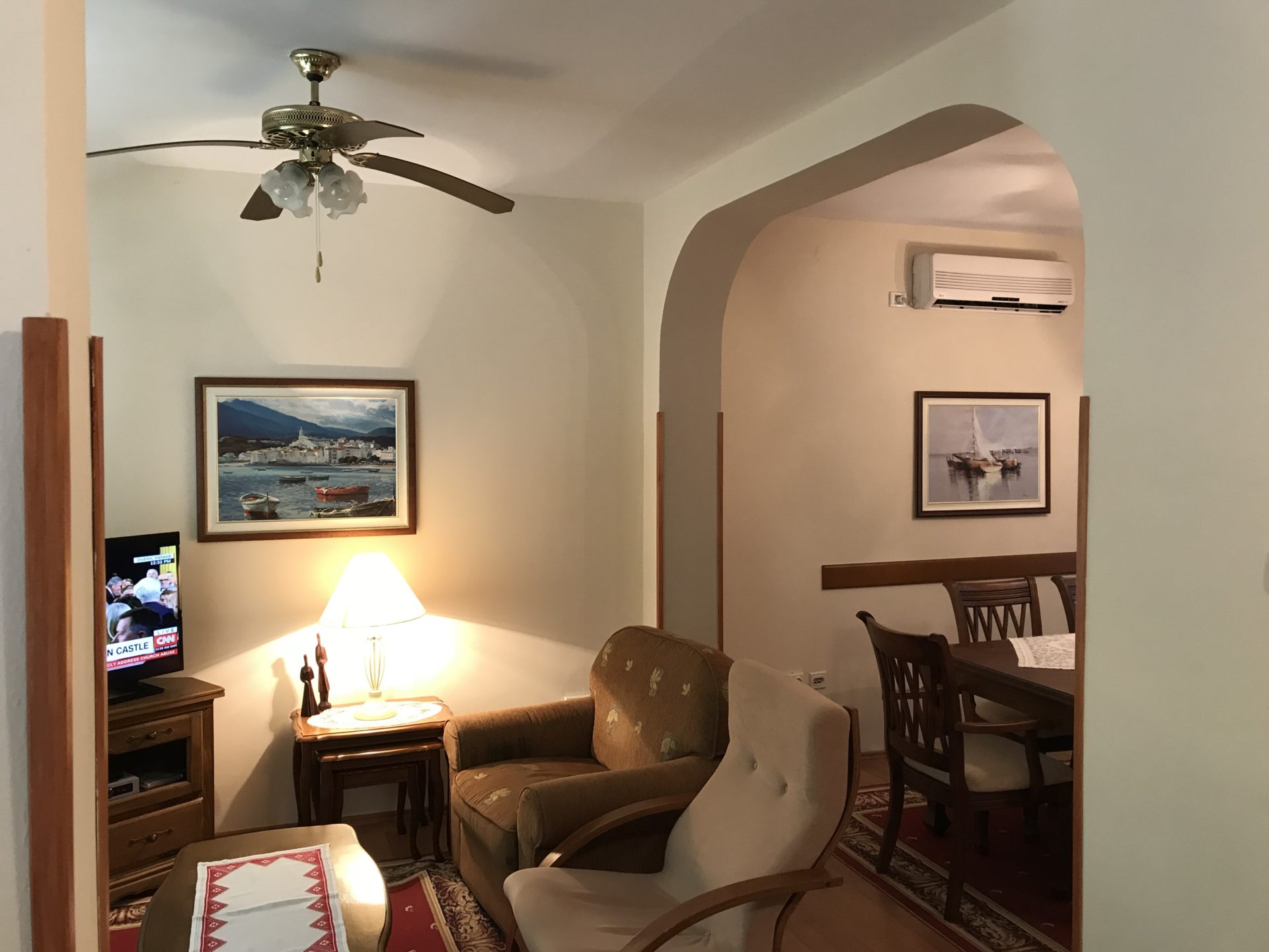 Gemütliches Wohnzimmer mit Essbereich in einem Haus in Kotor, Montenegro: weiche Sitzmöbel, Deckenventilator und Bilder.