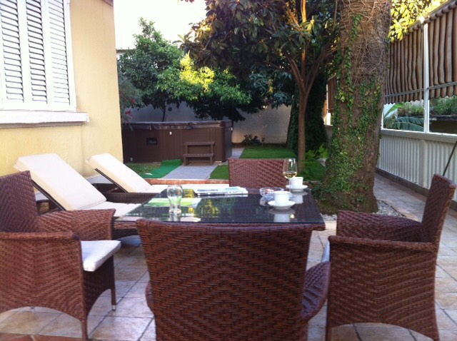 Terrasse des Hauses in Herceg Novi, Montenegro: Rattanmöbel, Liegestühle, Whirlpool im Garten und Blick auf das gepflegte Grundstück.