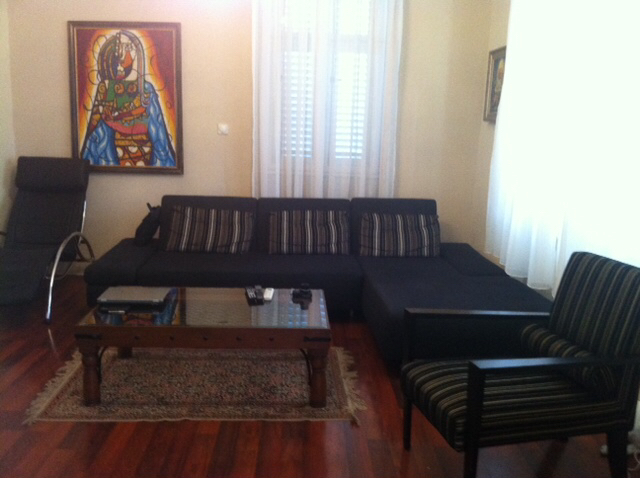 Wohnzimmer in einem Haus in Herceg Novi, Montenegro: dunkles Sofa, Sessel, Couchtisch und ein Bild an der Wand.