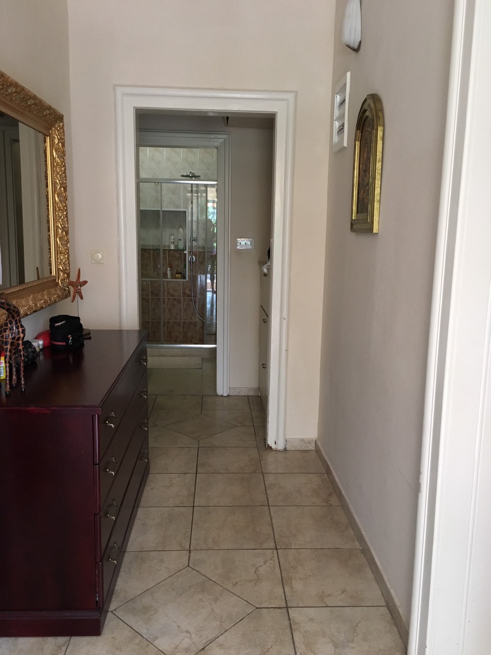 Flur mit dunkler Kommode und Spiegel im Haus in Herceg Novi, Montenegro, Blick auf das Badezimmer mit Duschkabine.