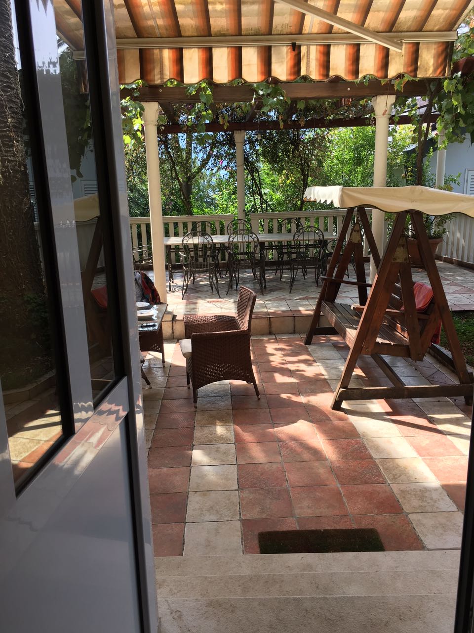 Gemütliche Terrasse mit Gartenmöbeln und Schaukel im Haus, Herceg Novi, Montenegro. Blick auf den schattigen Innenhof.