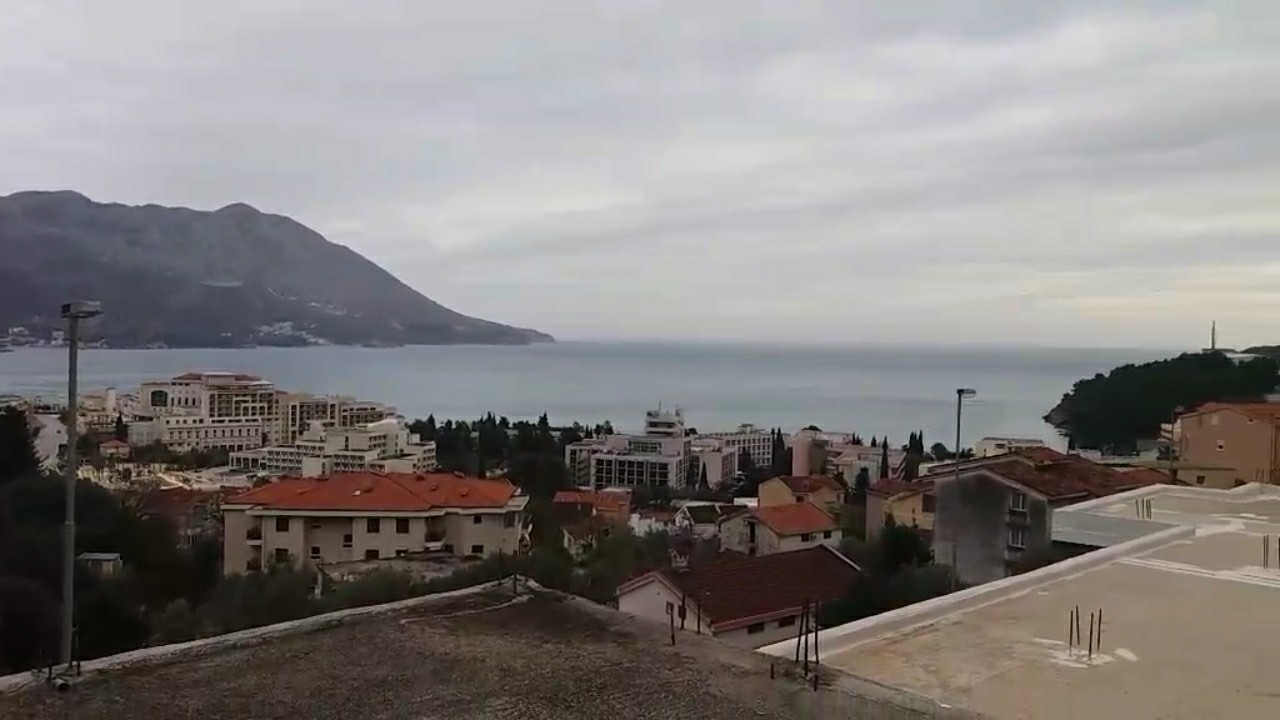 Panoramablick auf das Meer, die Berge und die Stadt Budva, Montenegro von der Terrasse des Hauses Nr. 1320, umgeben von mediterraner Bebauung.