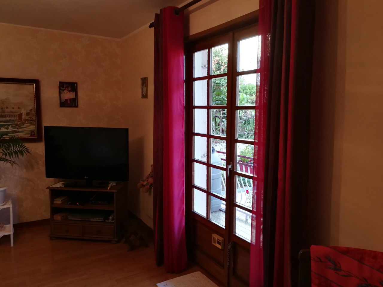 Wohnzimmer in einem Haus in Tivat, Montenegro: Holzmöbel, TV-Bereich und Zugang zur Terrasse mit Blick auf den grünen Garten.