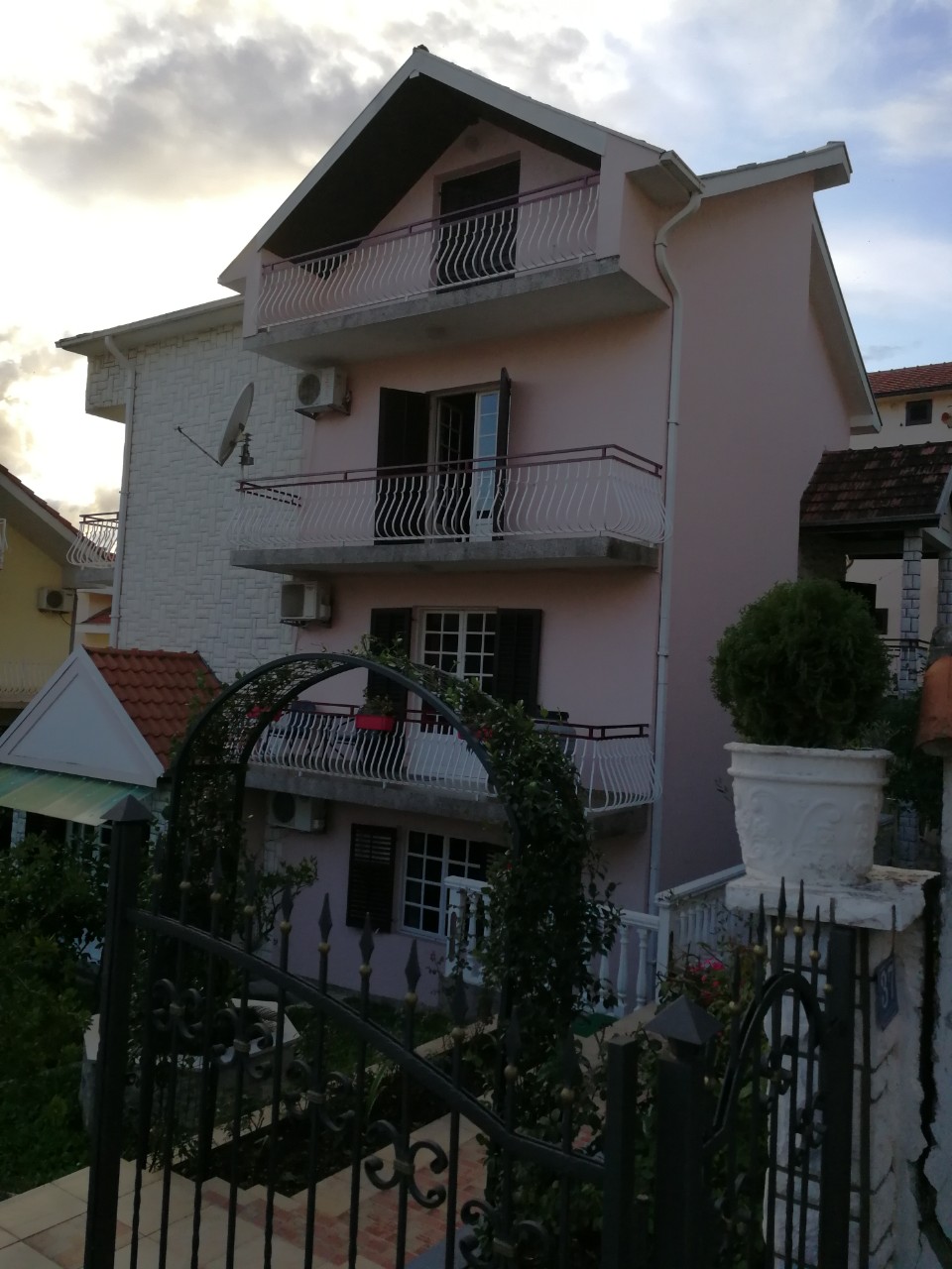 Dreistöckiges Privathaus mit Balkonen und schmiedeeisernem Tor in der Stadt Tivat, Montenegro. Blick auf die Fassade des Gebäudes.