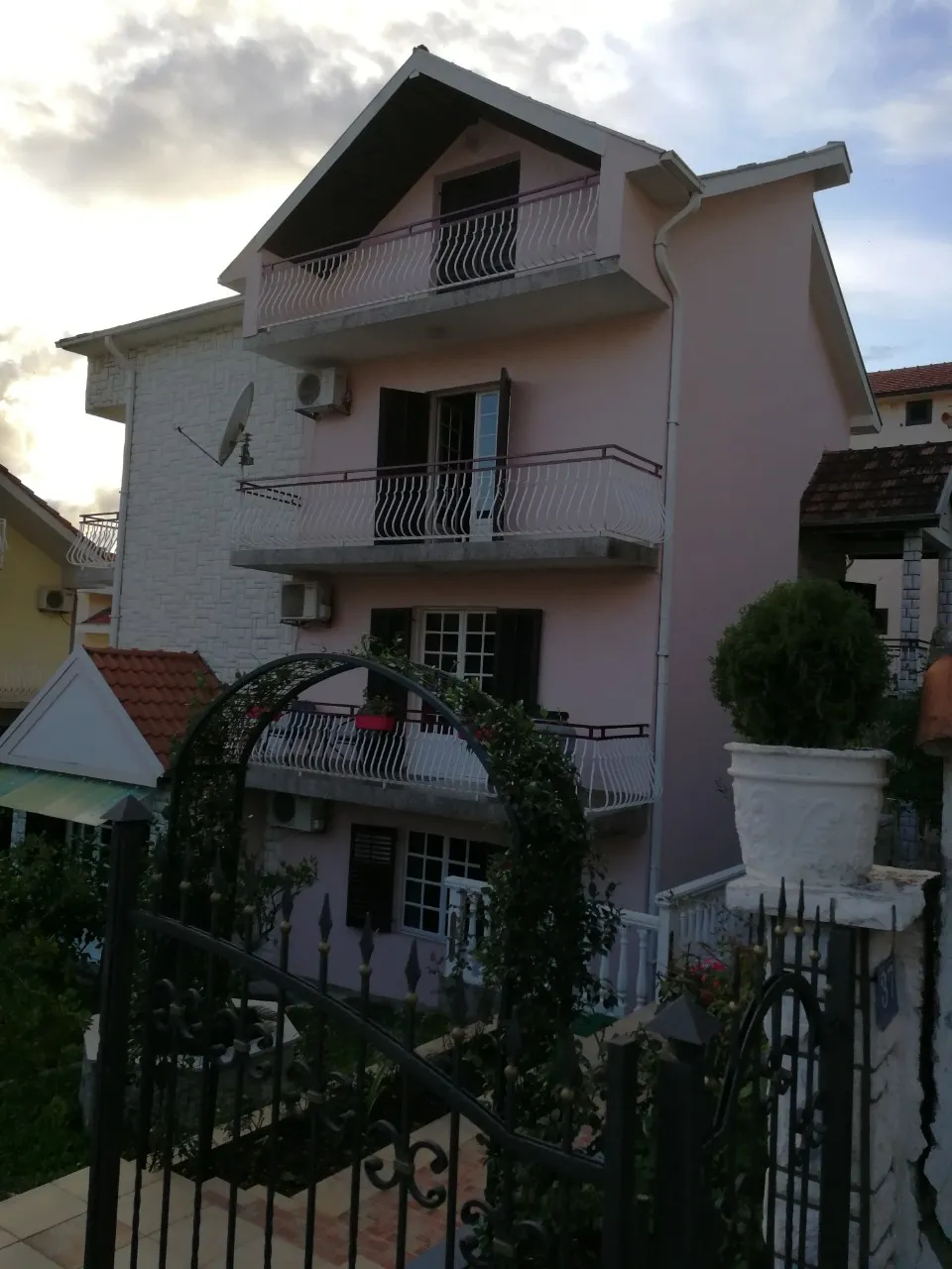 Dreistöckiges Privathaus mit Balkonen und schmiedeeisernem Tor in der Stadt Tivat, Montenegro. Blick auf die Fassade des Gebäudes.