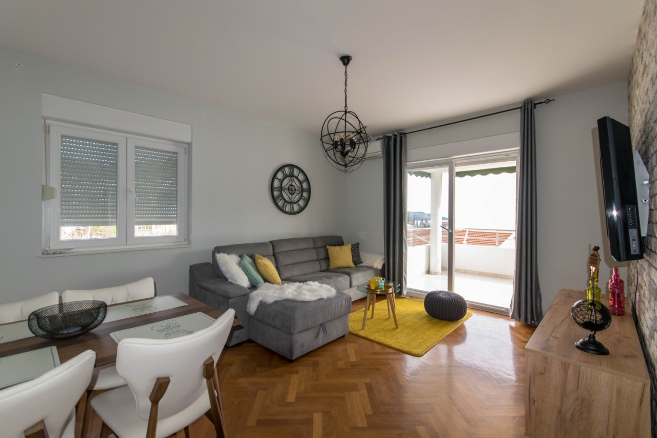 Modernes Wohnzimmer mit grauem Sofa und Zugang zur Terrasse in einer Wohnung in Herceg Novi, Montenegro.