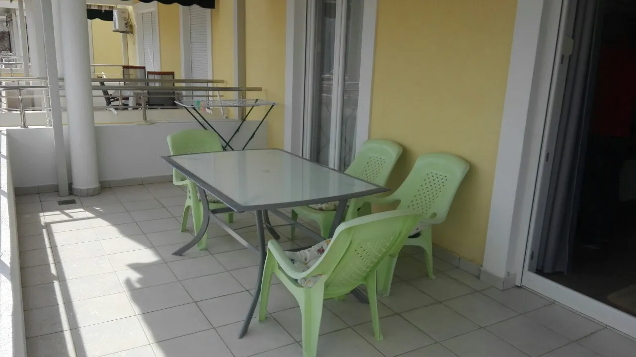 Ein hellgrüner Gartentisch und vier passende Stühle auf einem sonnigen Balkon.
