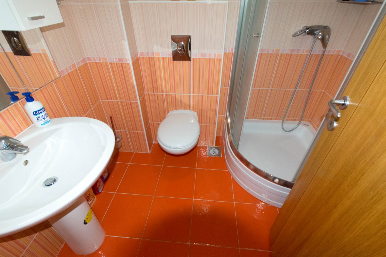 Badezimmer in einer Wohnung in Herceg Novi, Montenegro: Duschkabine, Sanitäranlagen und Fliesen in Orangetönen.