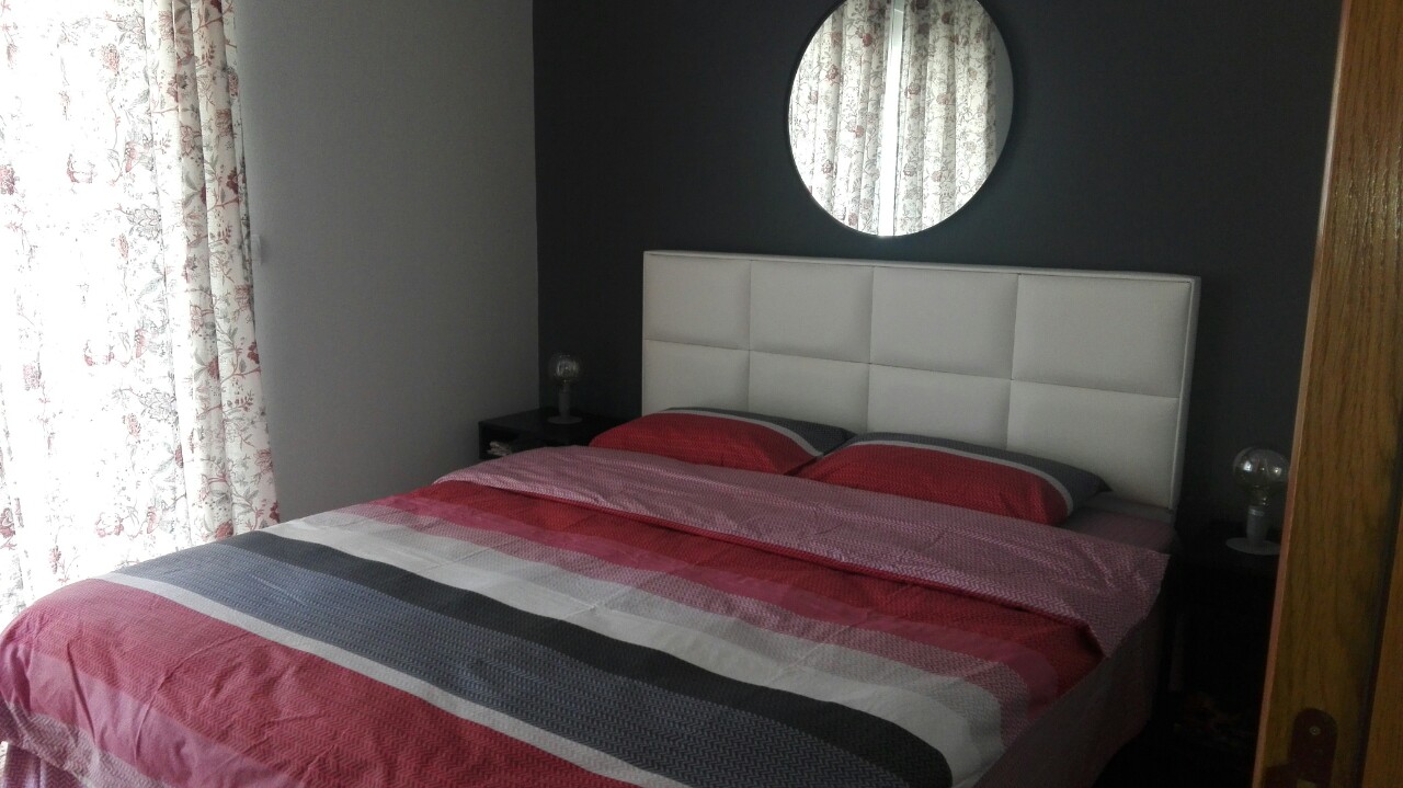 Schlafzimmer mit Doppelbett und rundem Spiegel in einer Wohnung in Herceg Novi, Montenegro. Modernes Interieur.