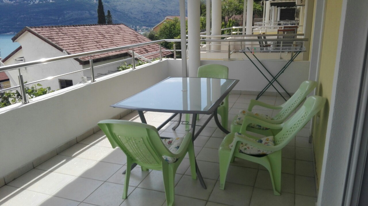 Balkon mit Möbeln und Meerblick in einer Wohnung, Herceg Novi, Montenegro: Esstisch und Kunststoffstühle.