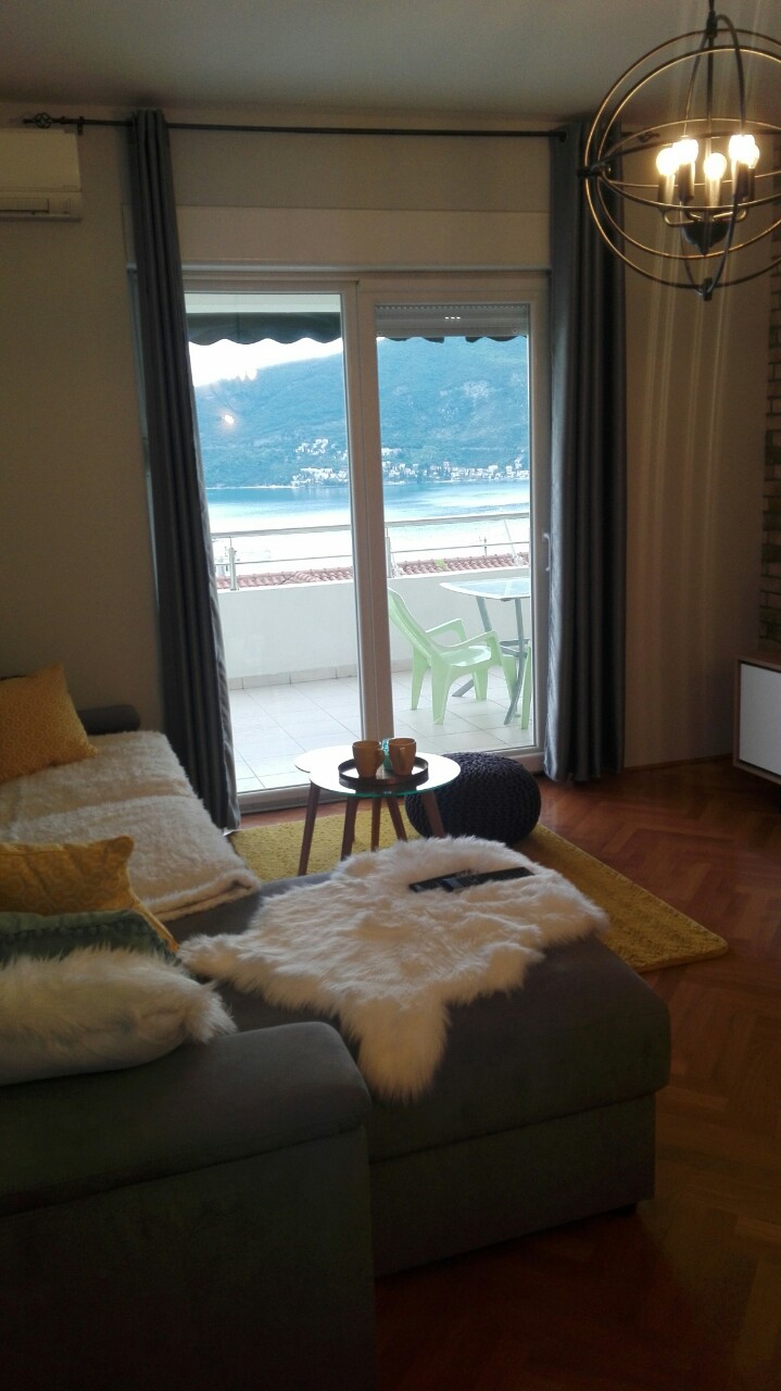 Wohnzimmer mit Meerblick in einer Wohnung in Herceg Novi, Montenegro: gemütliches Sofa, Terrasse und stilvolles Interieur.