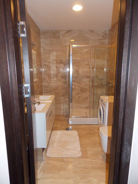 Modernes Badezimmer mit Duschkabine und Waschmaschine in einer Wohnung, Budva, Montenegro.