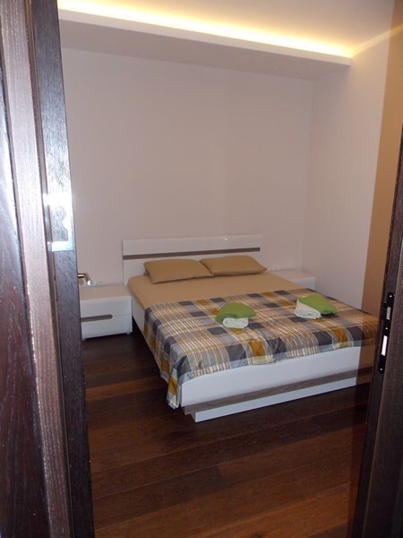 Schlafzimmer mit Doppelbett, weißen Möbeln und Parkettboden in einer Wohnung in Budva, Montenegro.