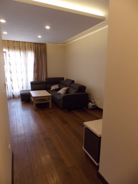 Wohnzimmer mit Ecksofa und Parkettboden in einer Wohnung in Budva, Montenegro. Modernes Interieur mit Beleuchtung.