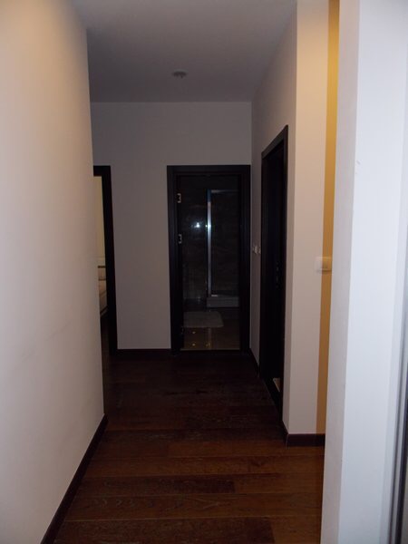 Flur in einer modernen Wohnung in Budva, Montenegro: helle Wände, dunkle Innentüren und Parkettboden.
