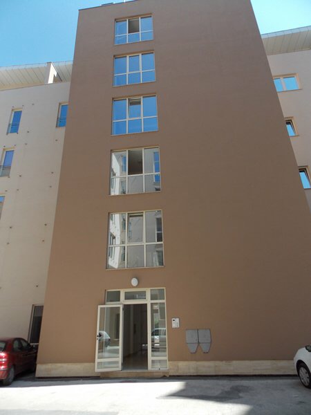Fassade eines modernen Mehrfamilienhauses in Budva, Montenegro: beige Wände, Panoramafenster und Eingangsbereich.