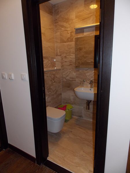 Modernes Badezimmer mit weißer Sanitärkeramik und Fliesenverkleidung in einer Wohnung in Budva, Montenegro.