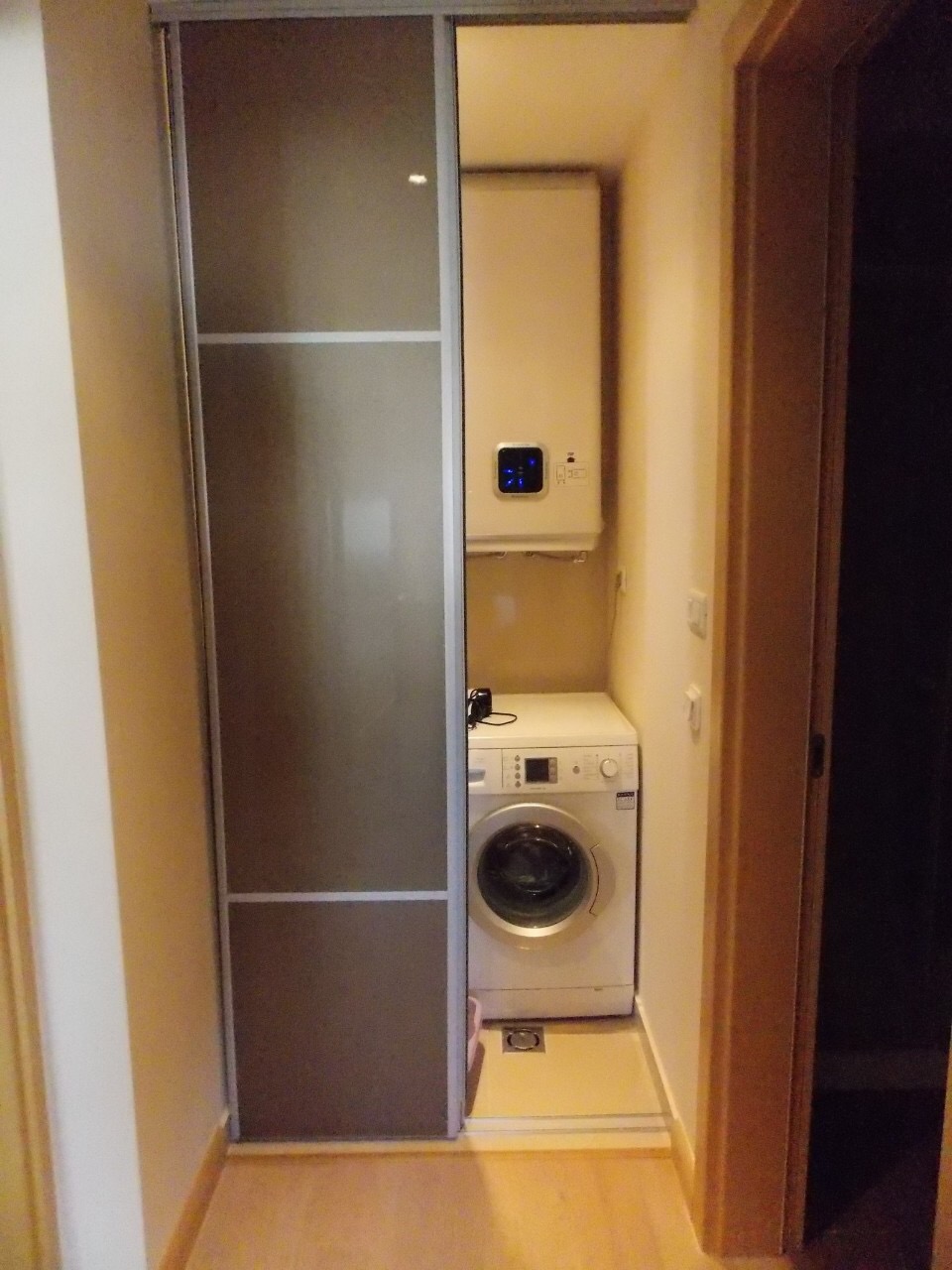 Ekonomska niša sa veš mašinom i bojlerom u stanu u Budvi, Crna Gora, zatvorena kliznim vratima.