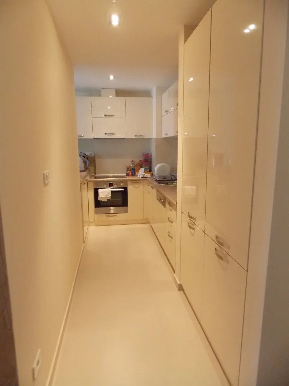 Moderne helle Küche mit Hochglanzfronten in einer Wohnung in Budva, Montenegro, mit eingebauten Elektrogeräten.