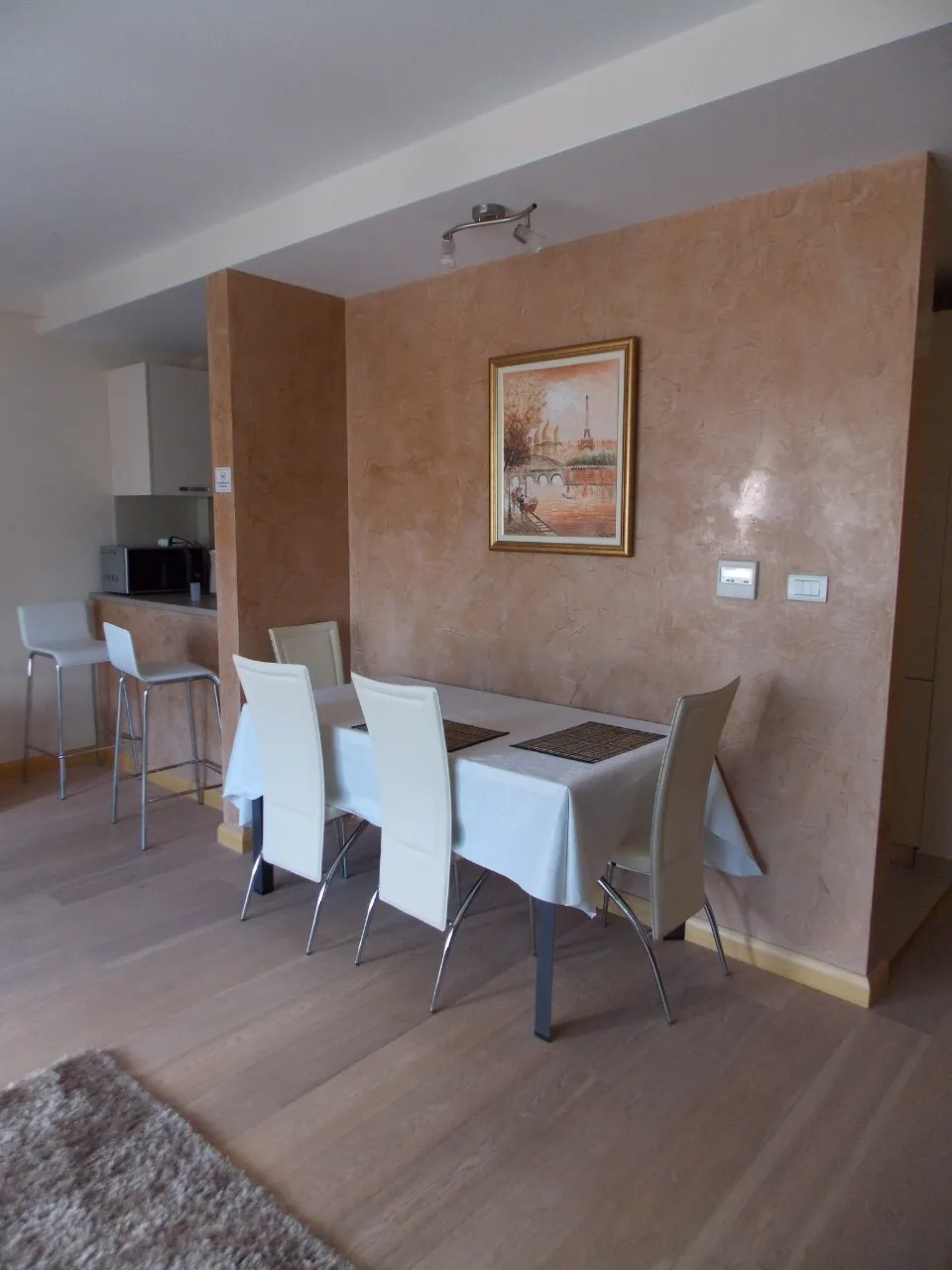 Wohnzimmer mit Essbereich in einer Wohnung in Budva, Montenegro: helle Möbel, dekorativer Putz und Parkett.