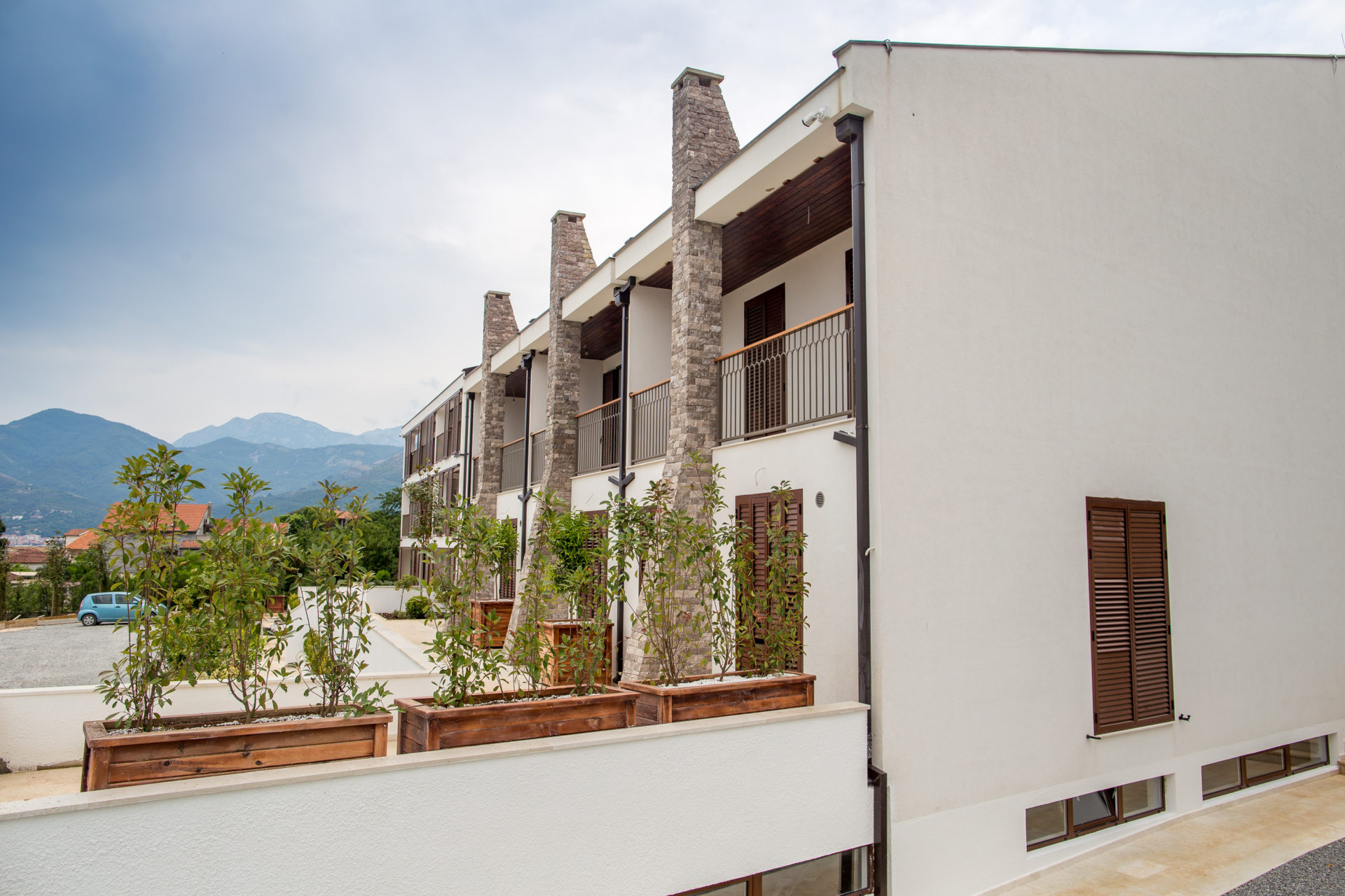 Moderner Wohnkomplex in Tivat, Montenegro: Fassade mit Steinverkleidung, Balkonen und Bergblick.