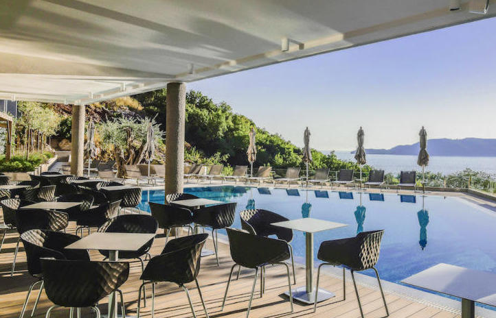 Offene Terrasse mit Pool und Meerblick in Kamenovo, Montenegro: Tische, Korbstühle und Liegen am Wasser.