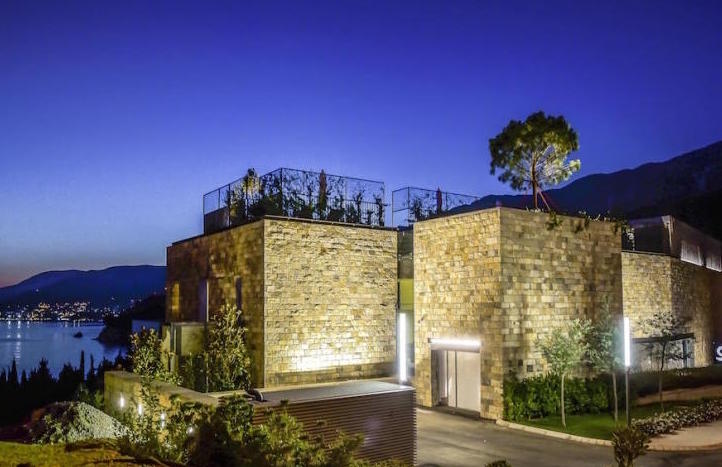 Moderne Villa mit Steinfassade und Dachterrasse in Kamenovo, Montenegro, Meerblick am Abend.
