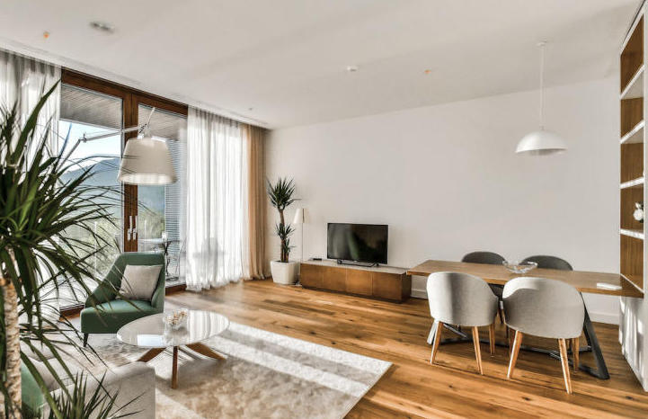 Modernes Wohnzimmer mit Panoramafenstern in einer Wohnung in Kamenovo, Montenegro: helles Interieur, Holzboden und Möbel.