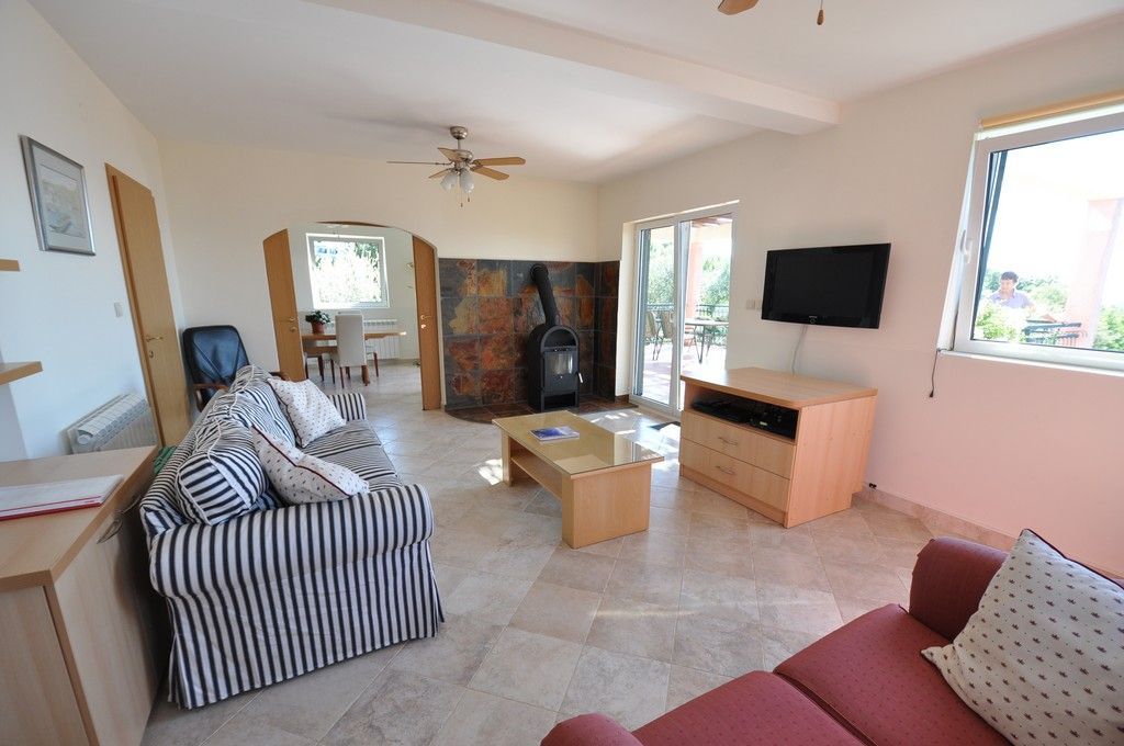 Wohnzimmer mit Kamin, Polstermöbeln und Zugang zur Terrasse in einer Villa in Tivat, Montenegro. Helles Interieur mit Fliesen.